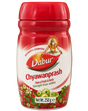 Red jar of Dabur Chyawanprash on a white surface with a brown cardboard background